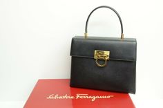 Salvatore Ferragamo Nero Pebble Calf 21-8791 0195479 Gold Plated, Leather Removable Strap Shoulder Bag Ladies, Womens, Female Push Through Logo Closure Manufactured: Italy Serial No.: AF-21 0290 Width: 25.5 cm Height: 19.5 cm Depth: 10.5 m Handle Drop: 11.5 cm ----- CONDITION RANKING SCALE S : New or new without a tag. SA : Excellent condition. (Like New - little to no use) A :  Good condition, barely used with few to no imperfections. B : There is a sense of overall use, with some minor damages Pre-owned Satchel For Formal Occasions, Pre-owned Top Handle Bags For Formal Occasions, Elegant Pre-owned Rectangular Bag, Pre-owned Elegant Top Handle Bag, Elegant Pre-owned Top Handle Bag, Chic Pre-owned Leather Bag, Pearl And Diamond Ring, Top Handle Bags, Vintage Purse