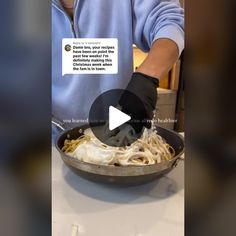 a person in a blue shirt and black gloves is cooking pasta