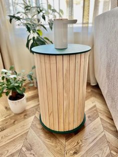 a wooden table sitting on top of a hard wood floor next to a planter