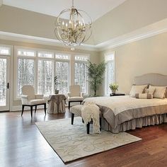 a large bed sitting in the middle of a bedroom next to two chairs and a chandelier