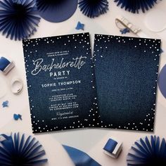 two black and white wedding cards on top of blue paper fans with confetti