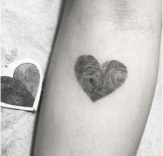 a heart shaped finger print tattoo on the left arm