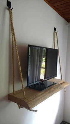 a flat screen tv sitting on top of a wooden shelf next to a wall mounted television