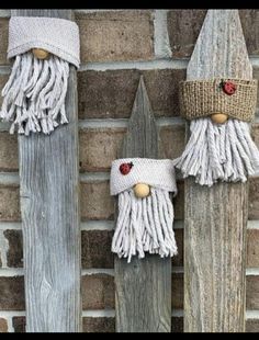 two gnomes made out of wooden boards on the side of a brick wall, one wearing a knitted hat