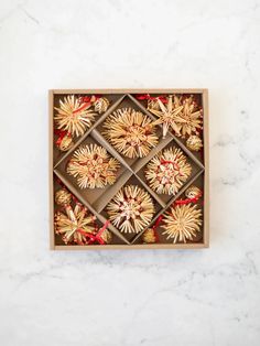 a wooden box filled with gold and red ornaments on top of a white marble counter