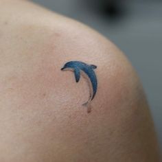 a small dolphin tattoo on the back of a woman's shoulder