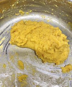 a metal bowl filled with yellow batter on top of a table