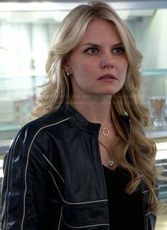 a blonde woman in a black leather jacket looking at the camera with serious expression on her face