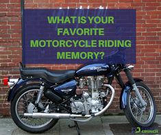 a motorcycle parked in front of a brick wall with a sign that says, what is your favorite motorcycle riding memory?