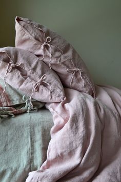 an unmade bed with pink linens and pillows on it's headboard