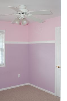 an empty room with pink walls and white ceiling fan