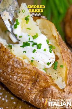 a baked potato with sour cream and chives on it is being eaten by a fork