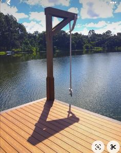 the shadow of a person standing on a wooden dock over water with trees in the background