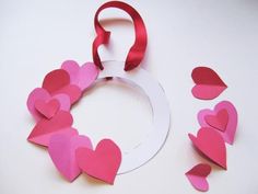 some paper hearts are on a white table with a red ribbon and scissors next to it