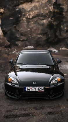 a black sports car parked in front of a rocky cliff