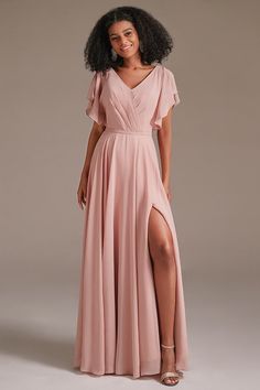 a woman in a long pink dress posing for the camera with her legs slited