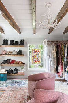 a pink chair sitting in front of a window next to a shelf filled with shoes