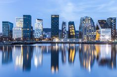 the city is lit up at night and reflecting in the water