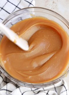 a glass bowl filled with peanut butter on top of a white and black checkered towel