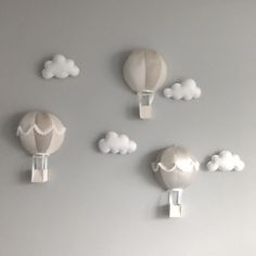 three hot air balloons floating in the sky with clouds around them on a gray wall