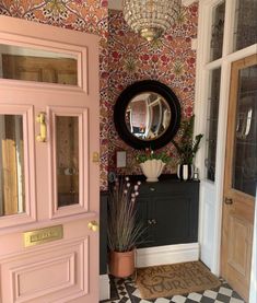 a pink door and mirror in a room with black and white checkered flooring