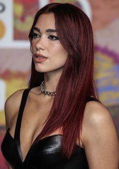 a woman with long red hair wearing a black leather dress and choker on her neck