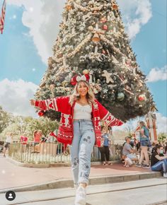 a woman is walking in front of a christmas tree at universal studios hollywood, california