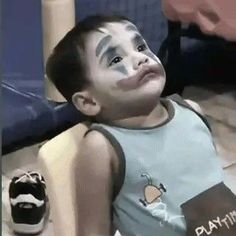 a young boy with his face painted like an apple is laying on the floor and looking up