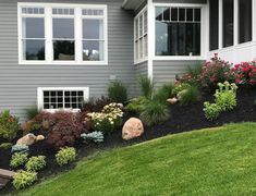 a house that has some flowers in the front yard and landscaping on the side of it