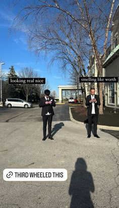 two men in suits are standing on the street