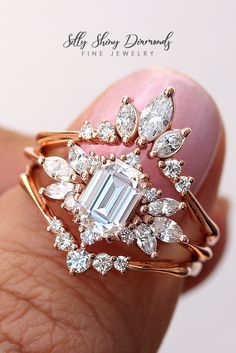 a close up of a person's hand holding a ring with an emerald stone