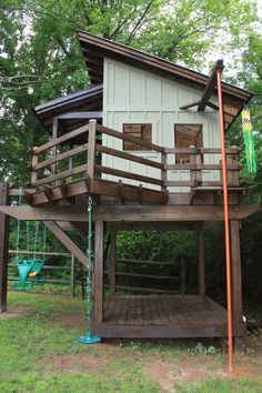 a tree house with a swing set on the deck and stairs leading up to it