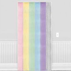 a rainbow colored curtain hanging on the side of a white wall in an empty room