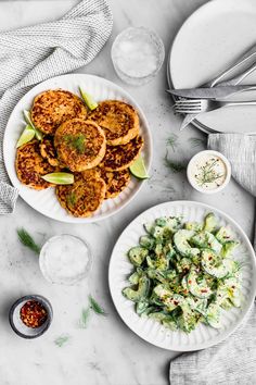 two plates with food on them next to silverware and utensils in bowls