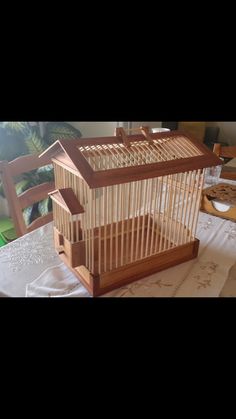 a bird cage sitting on top of a table next to a white cloth covered table