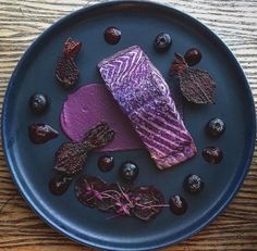 a piece of fish on a plate with blueberries