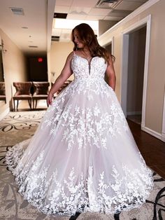 a woman in a white wedding dress standing on a carpeted floor with her hands behind her back