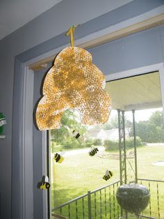 a yellow light hanging from the side of a window next to a green door with bees on it