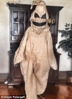 a stuffed animal that is standing in front of a wooden cabinet with an evil face on it's head