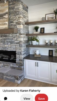 a living room with a stone fireplace and shelves on the wall, along with white cabinets