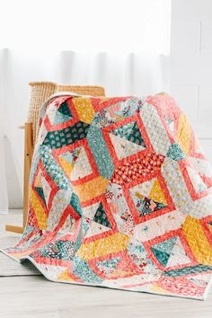 a colorful quilt on the floor next to a chair