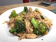 a white plate topped with meat and broccoli on top of a wooden table