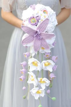 a bride holding a bouquet of white and purple flowers