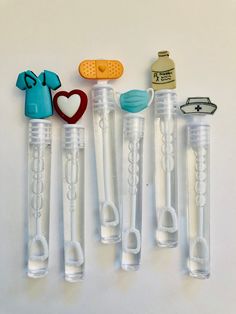 five plastic objects are arranged in a row on a white surface, including one with a heart and the other without