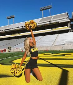 a cheerleader in black and yellow is dancing on the field at a football stadium