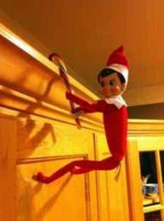 an elf is hanging on the wall holding a candy cane