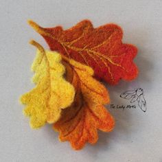 an orange and yellow leaf laying on top of a white surface