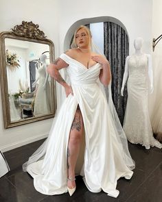 a woman standing in front of a mirror wearing a wedding dress with thigh high slit