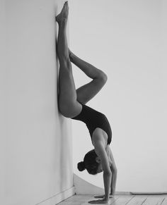 a woman is doing a handstand on the wall