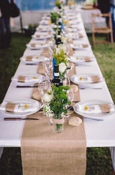 a long table is set up with place settings and flowers in vases on it